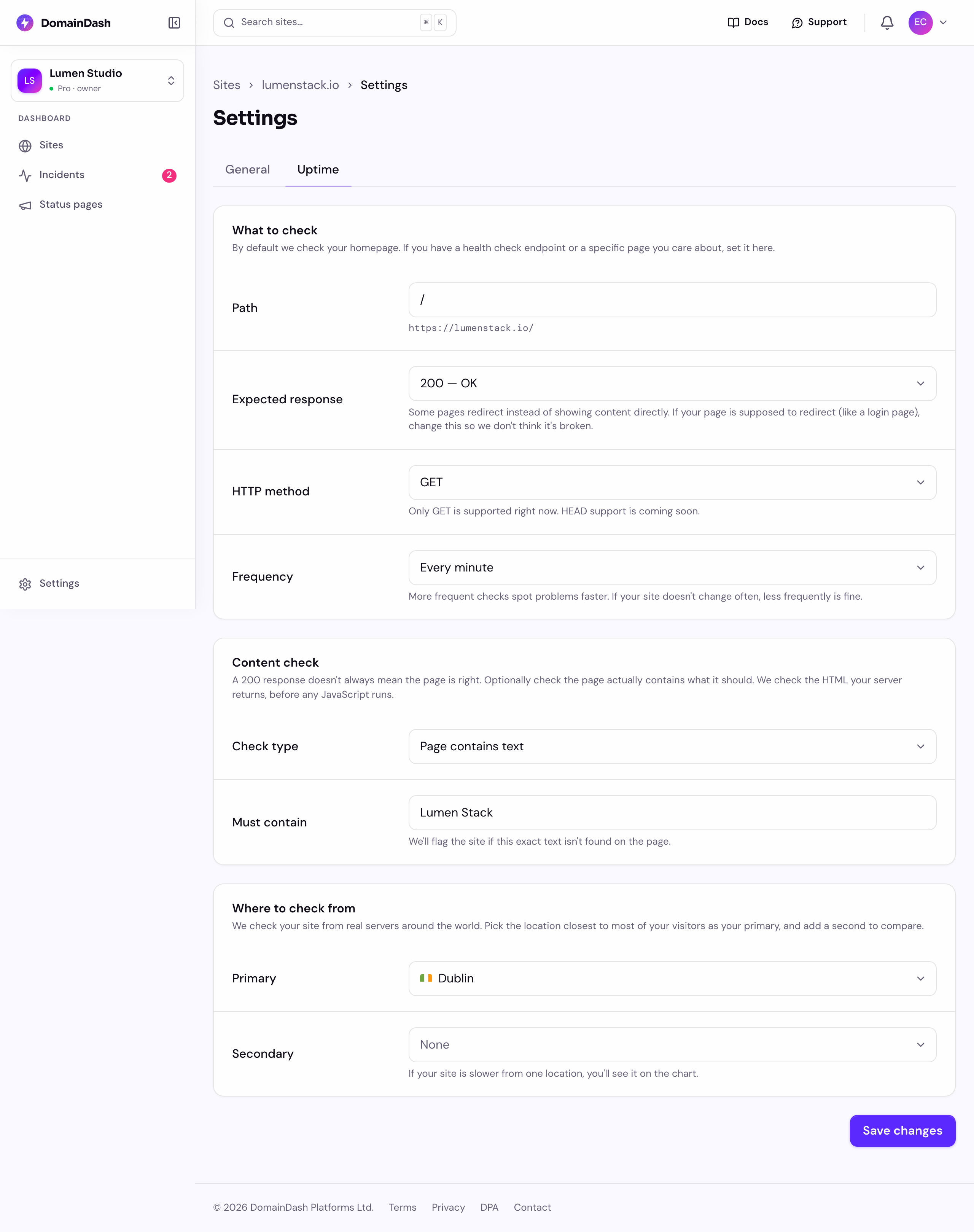 The uptime settings for a site in DomainDash, with a Content check section below the status check: a "Check type" set to "Page contains text" and a "Must contain" field reading "Lumen Stack", noting we check the HTML before any JavaScript runs